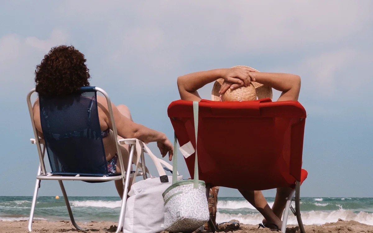 Urlaubsgäste auf Sonnenliegen am Meer und Ferienvilla in Moraira